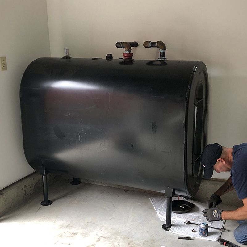 Domino Fuel technician installing a steel oil tank in a Long Island garage